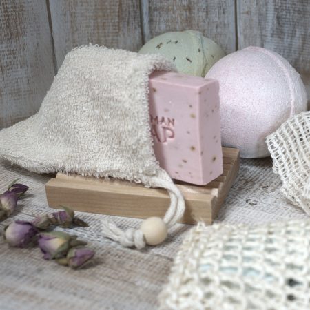 Handgemaakt blok olijfoliezeep in een natuurlijke washand op een houten zeepbakje puur, duurzaam en stijlvol gepresenteerd.